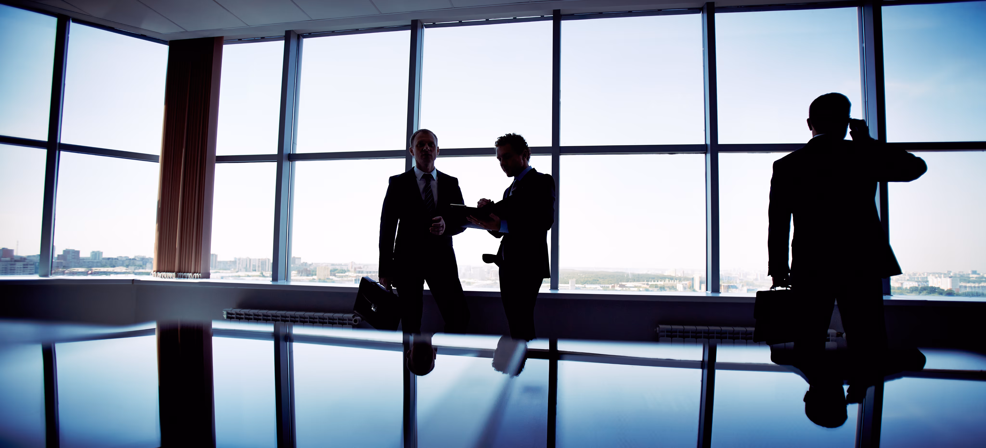 Colleagues in conversation against a Business Bay office window